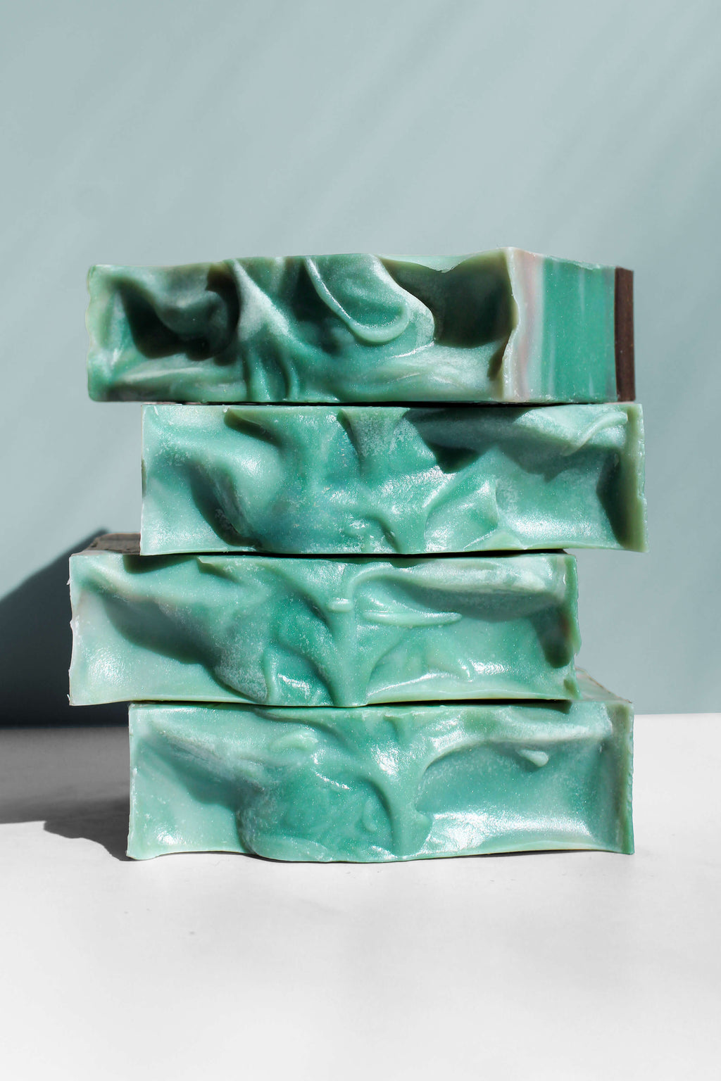 Stack of green soap bars on a white surface with a light gray background