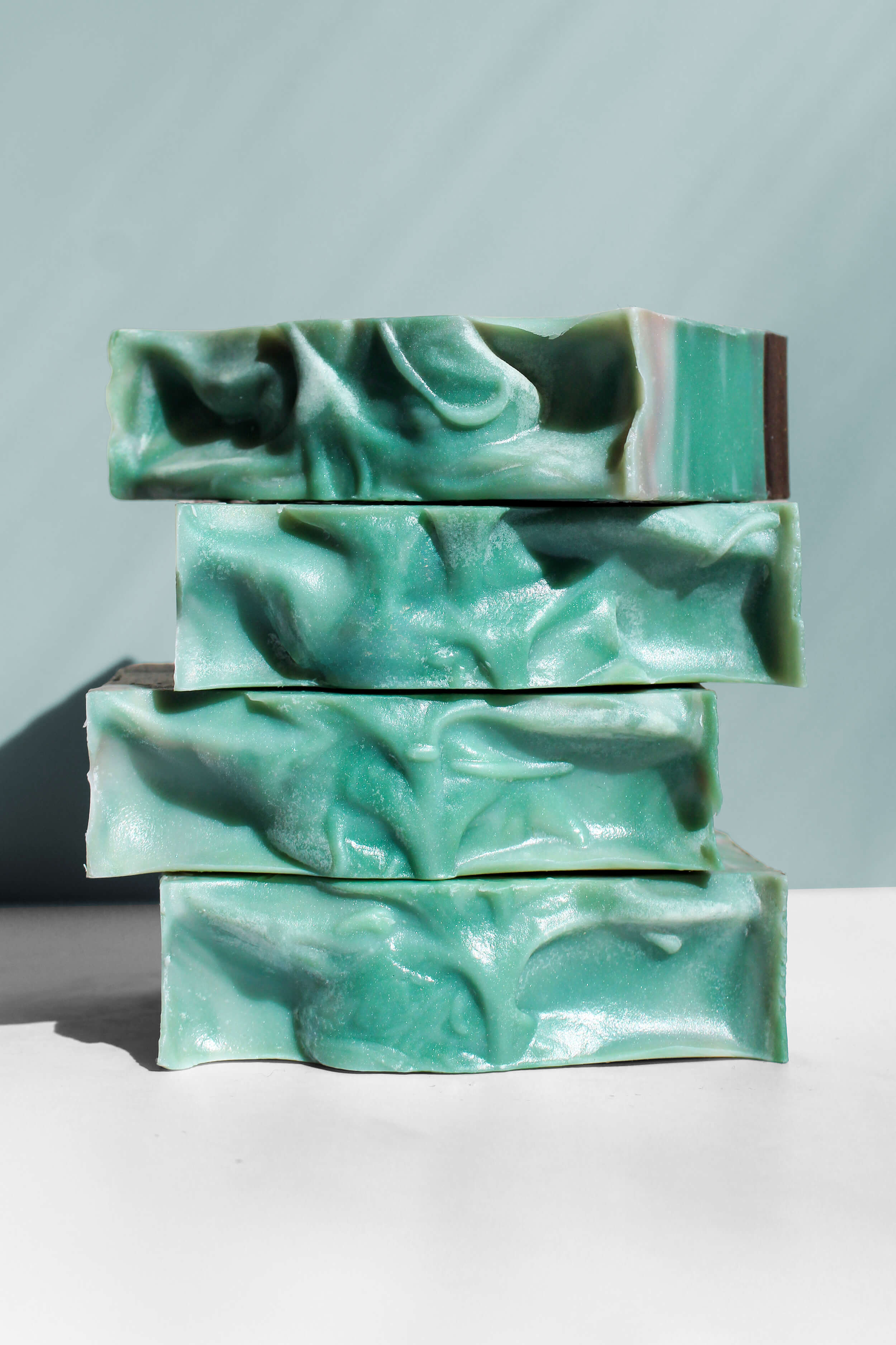 Stack of green soap bars on a white surface with a light gray background