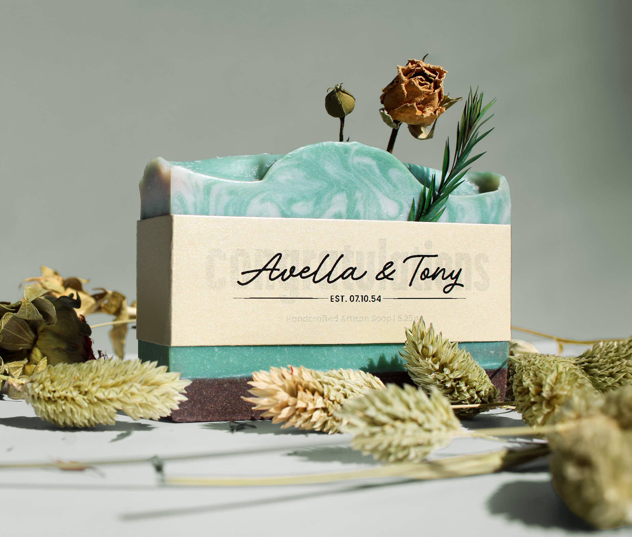 Bar of soap with a decorative label and dried flowers on a light background