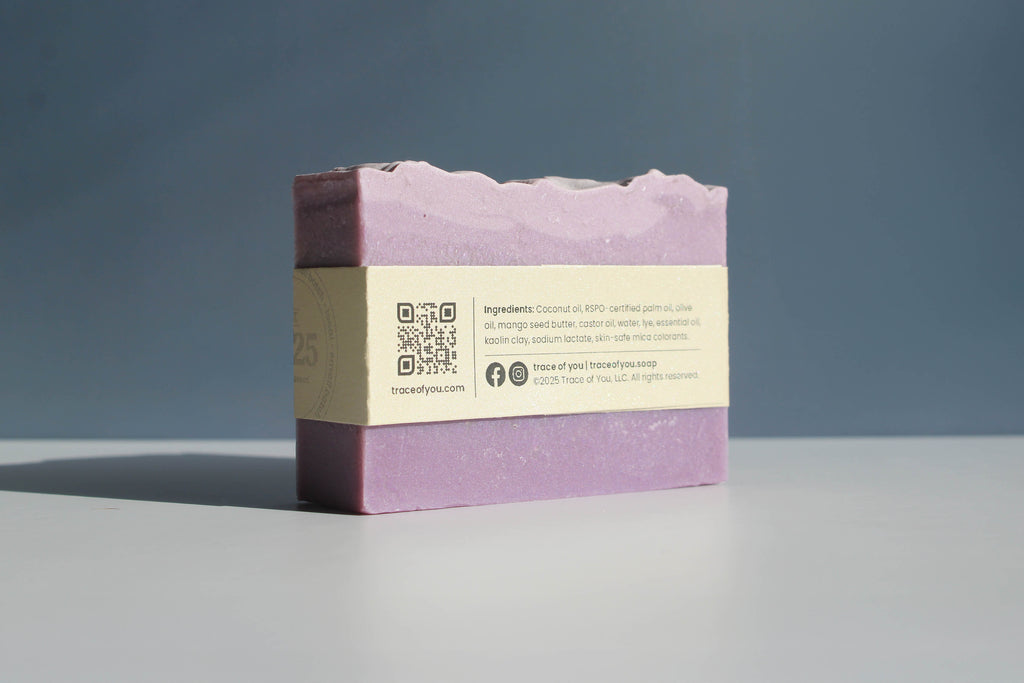 Purple soap bar with a label on a gray surface and blue background