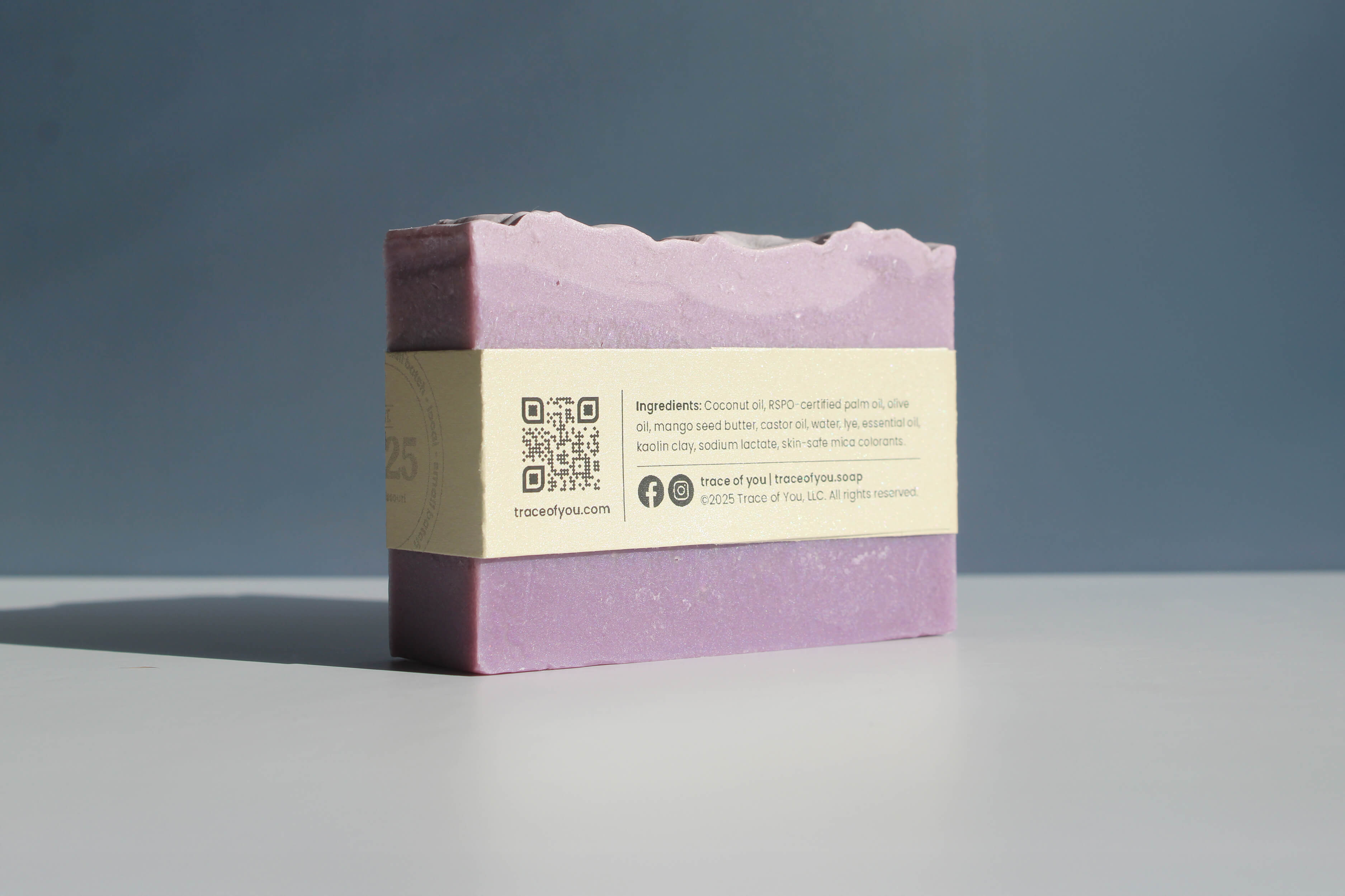 Purple soap bar with a label on a gray surface and blue background