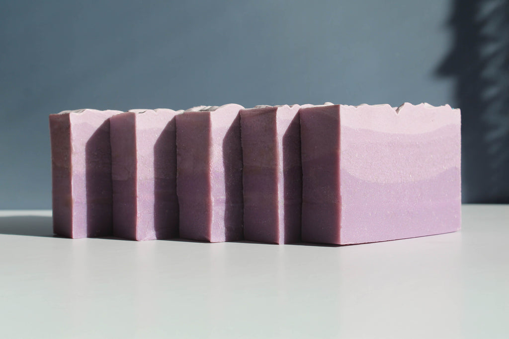 Stack of purple soap bars on a gray surface with a dark blue background