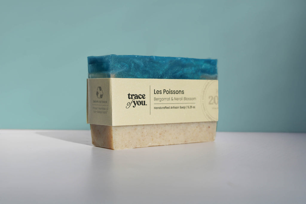 Bar of soap with a visible brand label on a light gray surface against a teal background