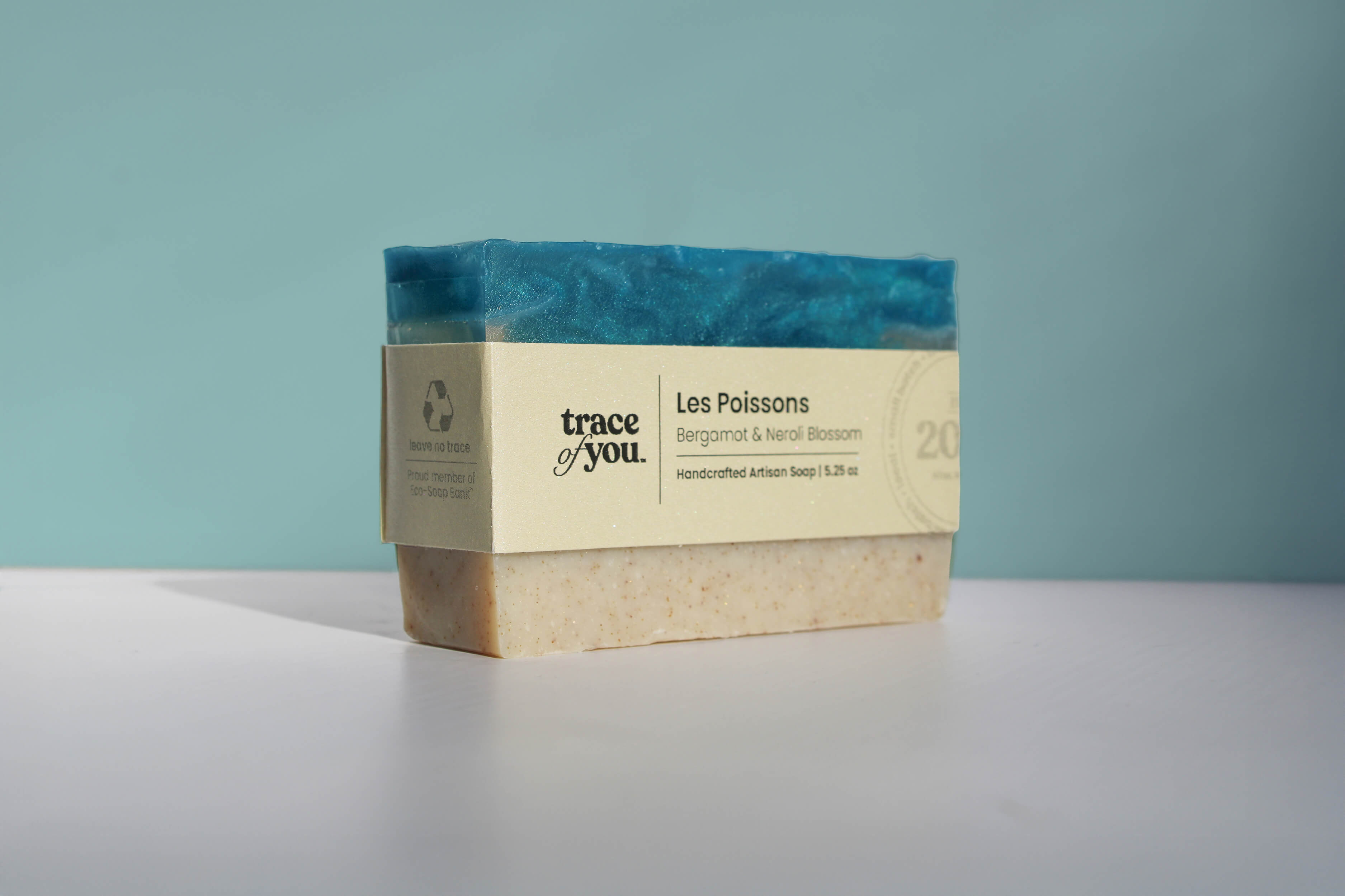 Bar of soap with a visible brand label on a light gray surface against a teal background