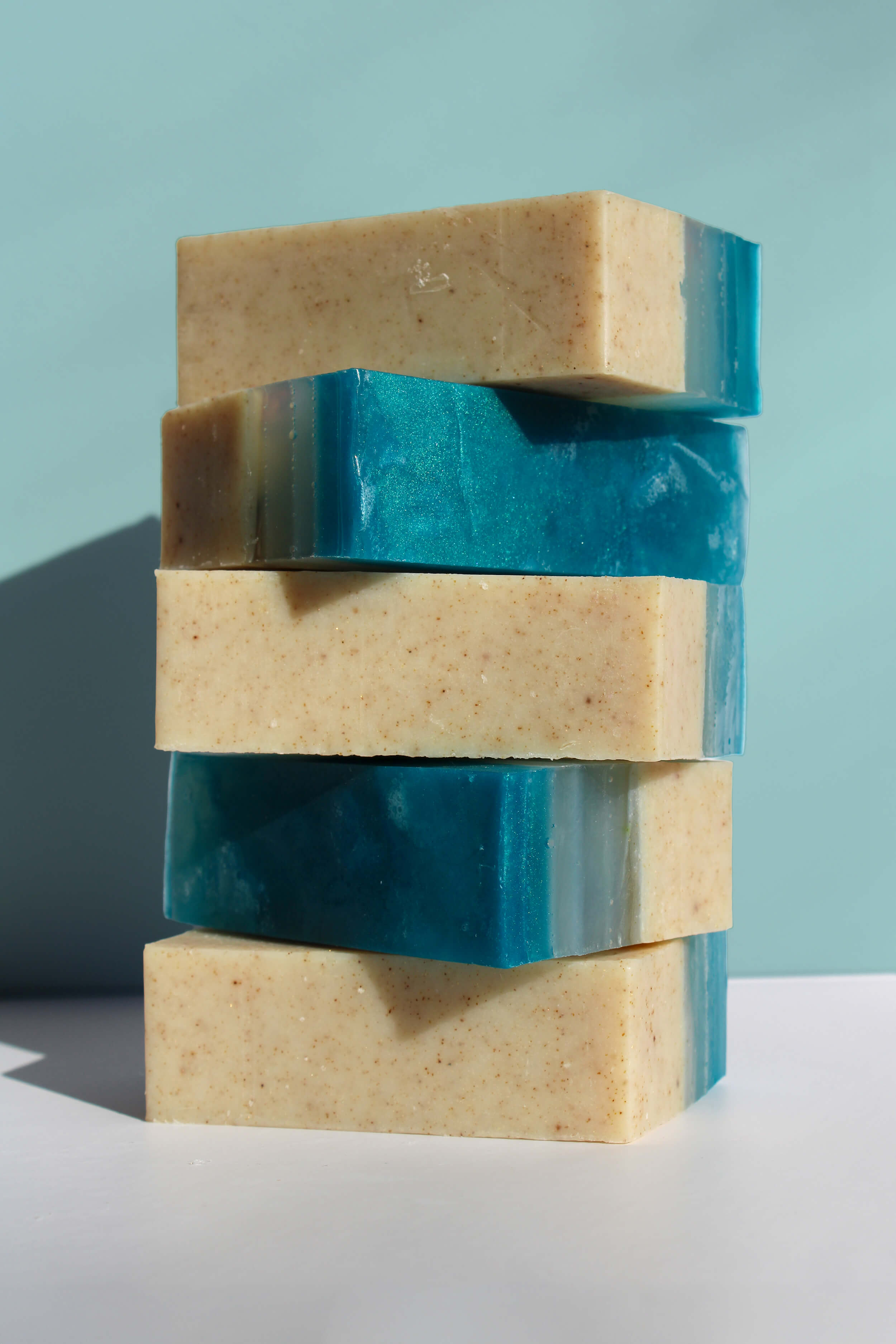 Stack of five handmade soap bars with a blue and beige color pattern on a light blue background.