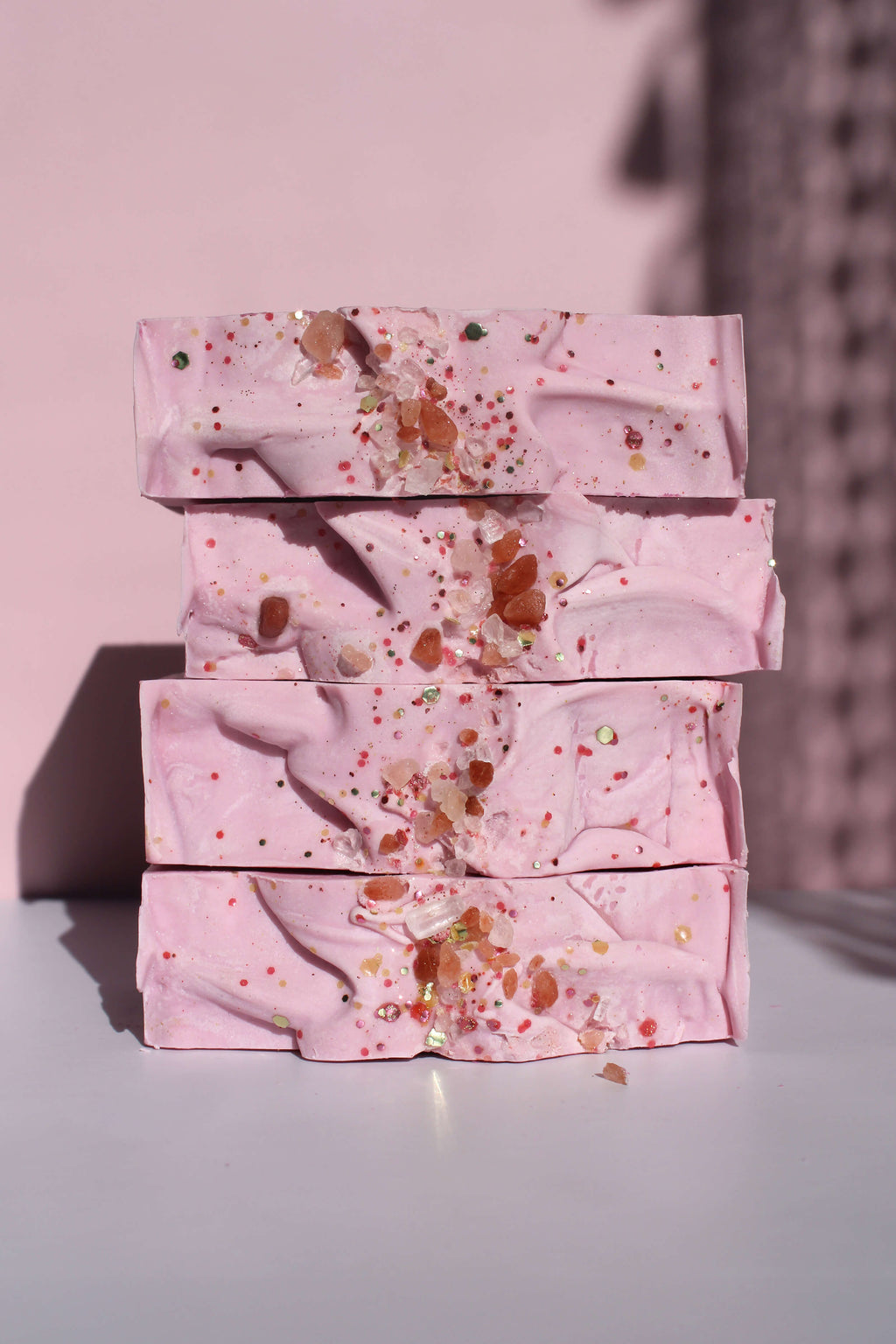 Stack of pink soap bars on a light surface with a pink background