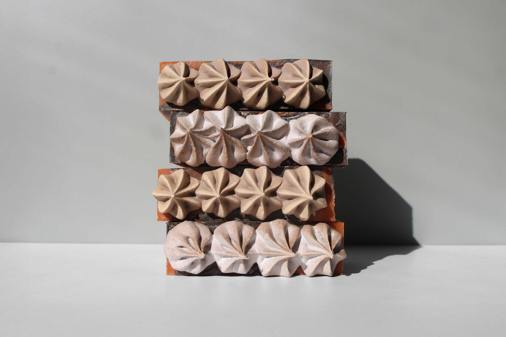 Three stacked soap bars with decorative top layers on a gray background