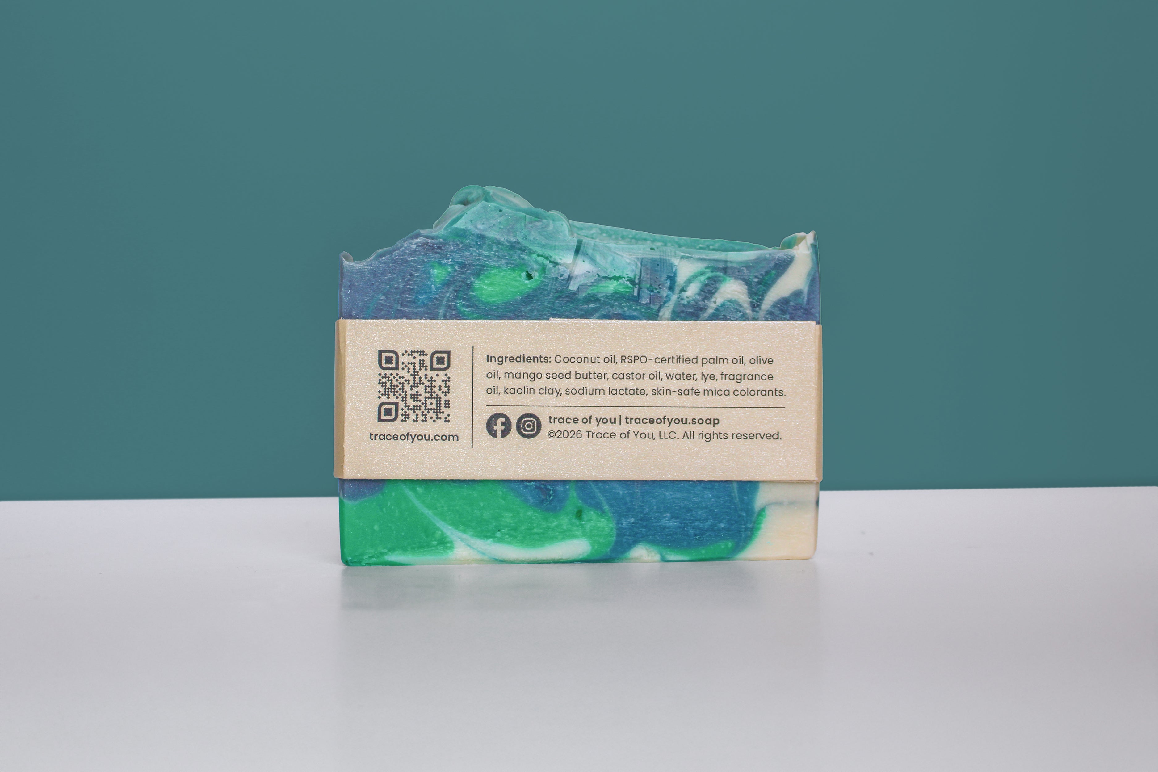 Bar of soap with a green and blue pattern on a white surface against a teal background