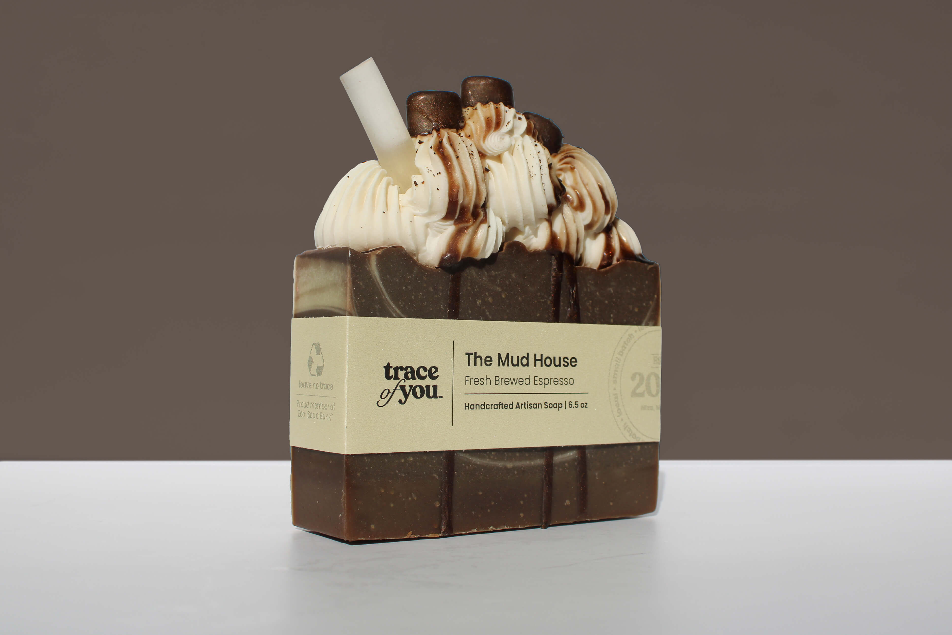 Bar of soap with frosting and espresso bean pieces on a gray background