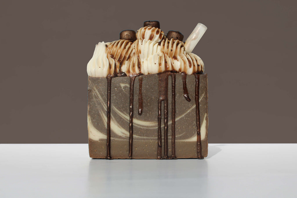 Espresso dessert soap with whipped cream and chocolate drizzle on a white surface with a brown background