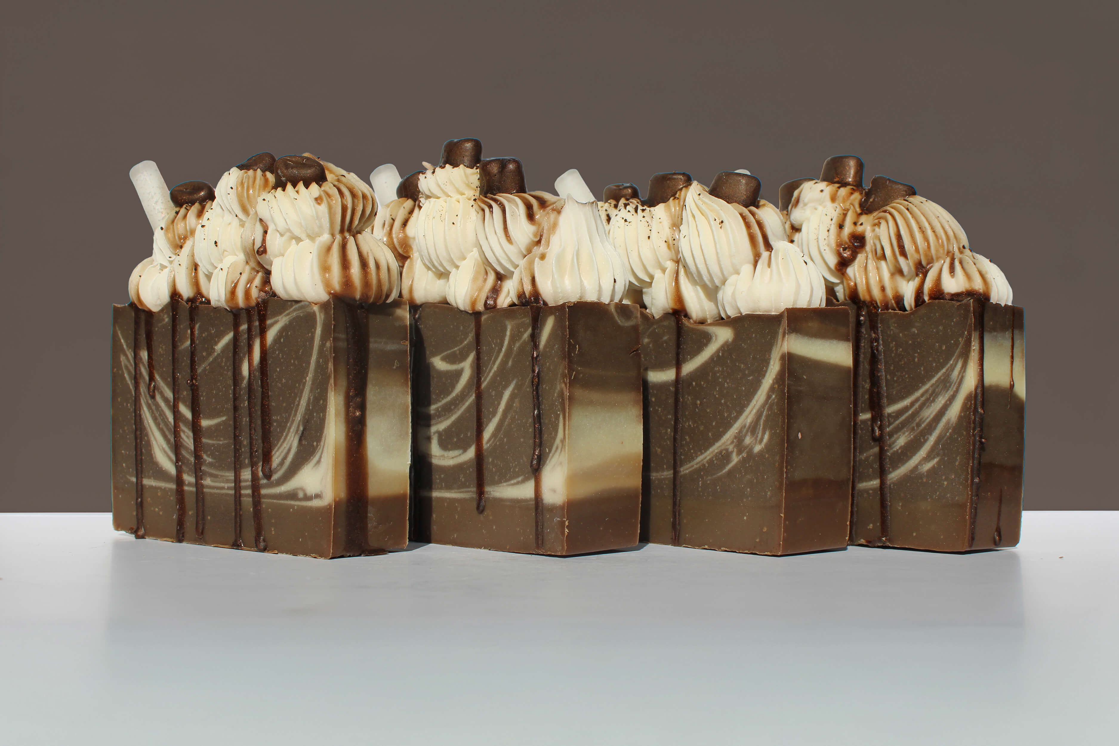 Row of chocolate soap bars with caramel and chocolate drizzle on a gray background