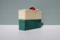 A bar of soap with a raspberry on top, on a gray background.
