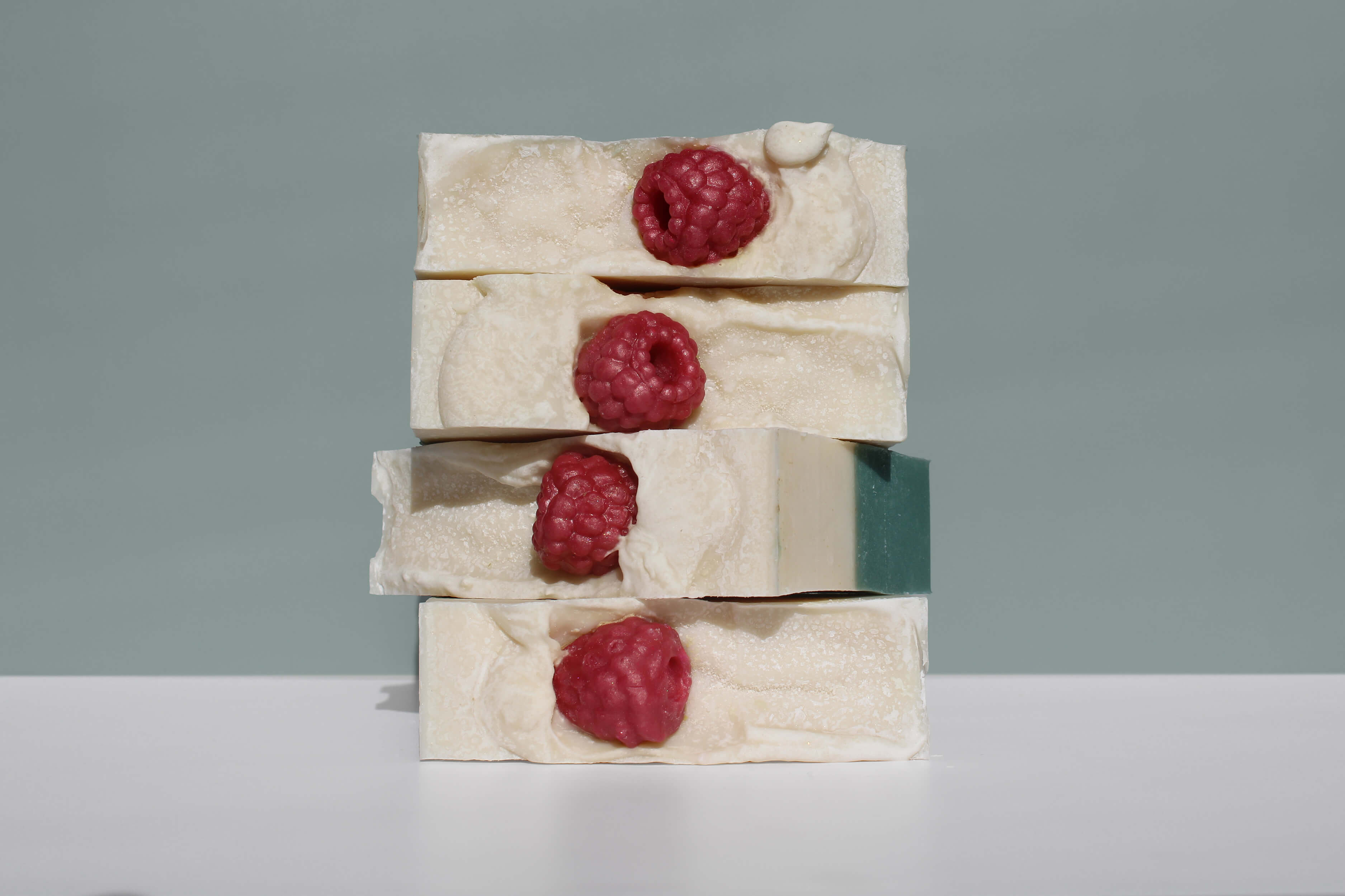 A stack of four soaps with raspberry embeds. 